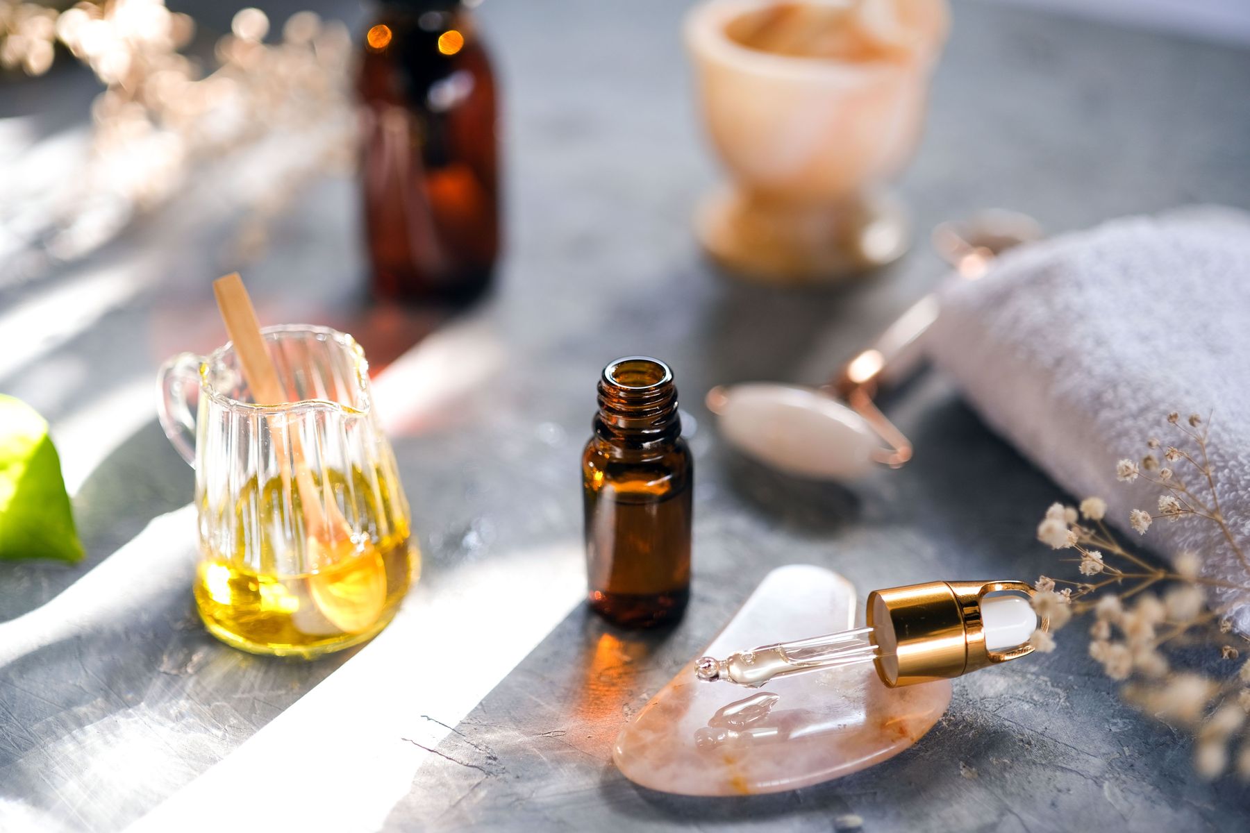 Massage oil, essential oil dropper, and healing stones on a treatment table