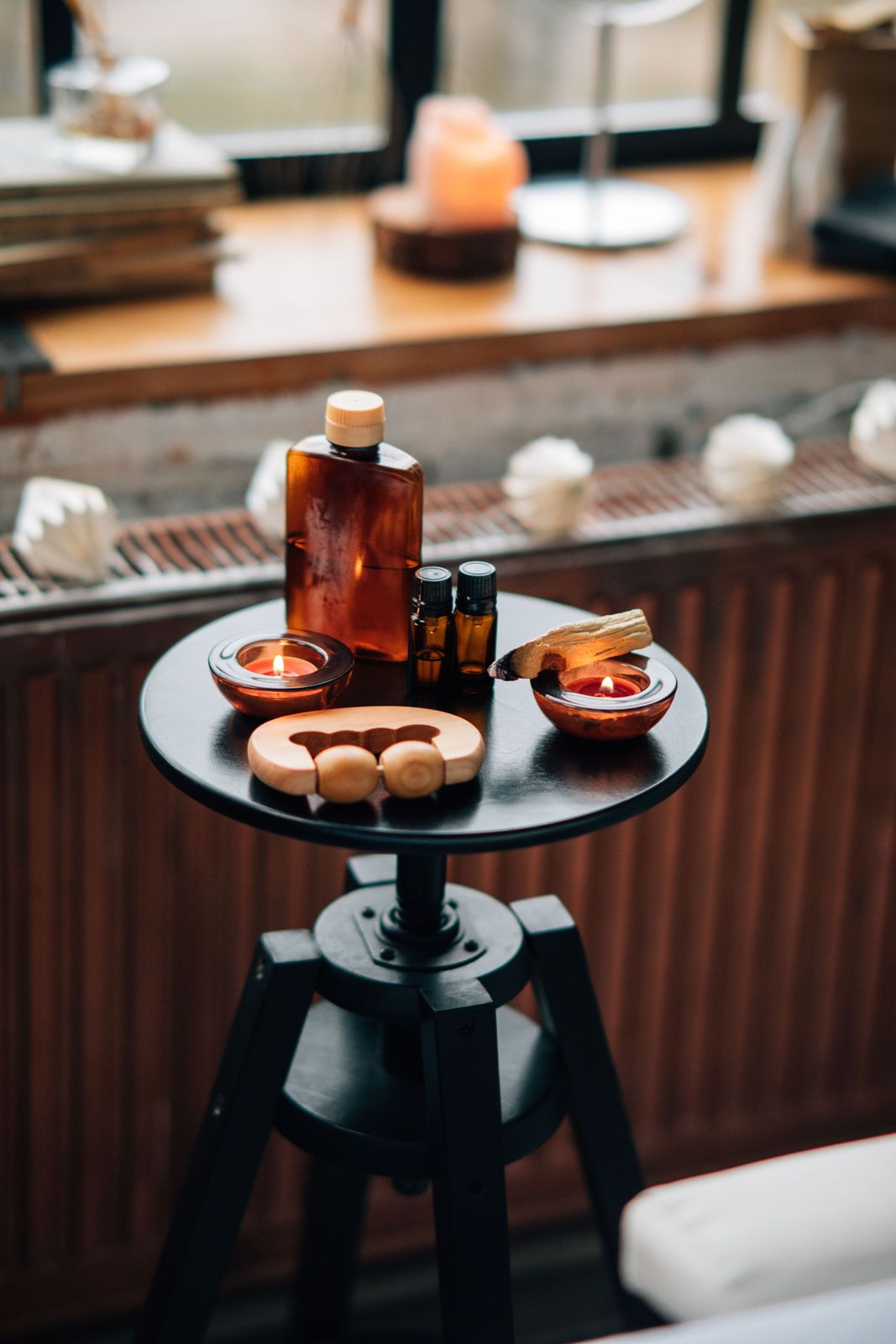 Amber massage oils, candles and a wooden roller arranged on a side table