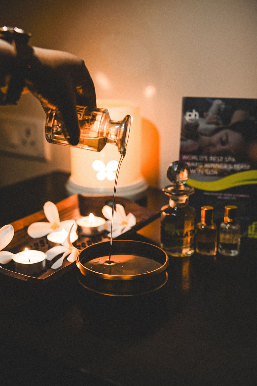 Warm oil poured into a brass bowl by candlelight